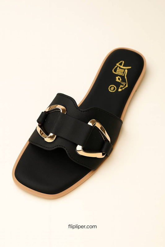 Pair of black sandals with gold buckles displayed on a beige background