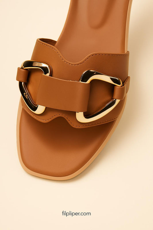 Pair of brown sandals with gold buckles displayed on a beige background