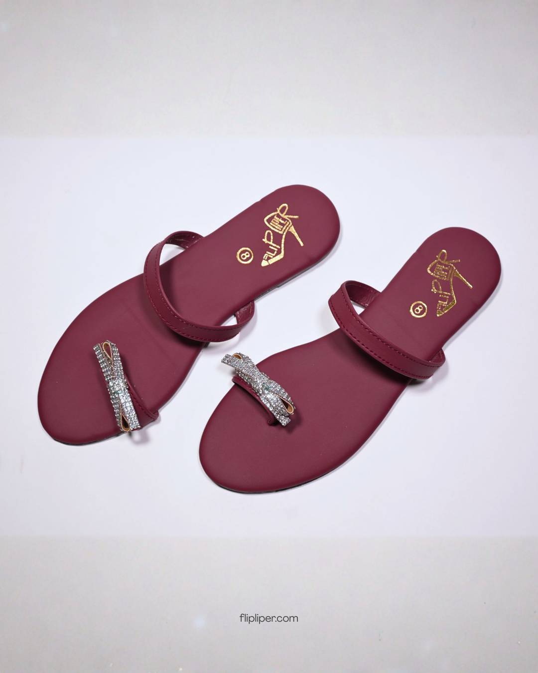 Red sandals with crystal embellishments displayed on a dark black background
