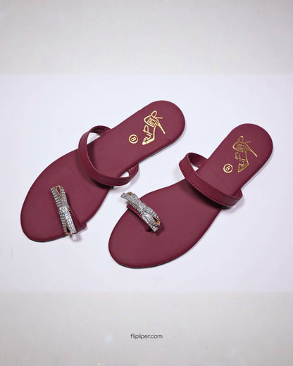 Red sandals with crystal embellishments displayed on a dark black background
