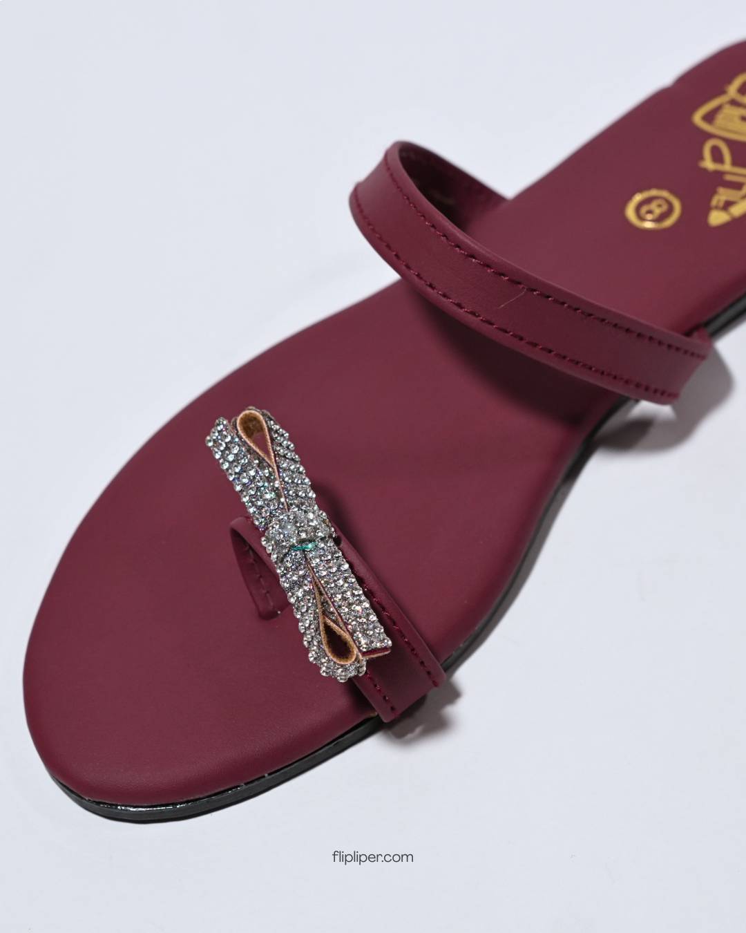 Red sandals with crystal embellishments displayed on a dark black background
