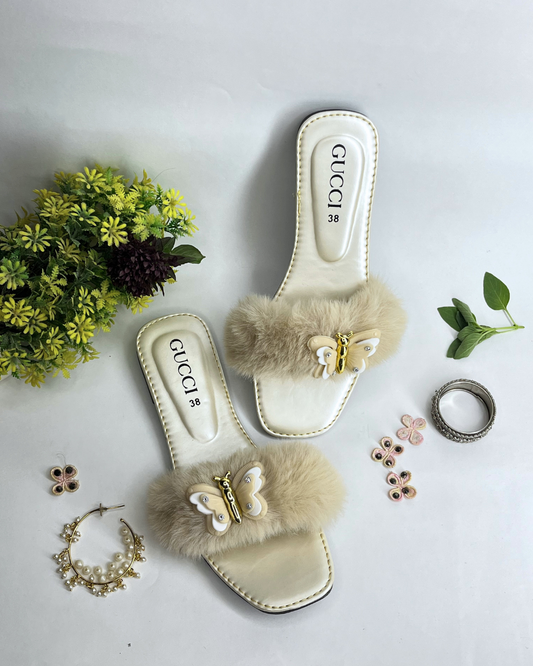 Women comfort slides with fluffy fur strap and butterfly embellishment on a light background