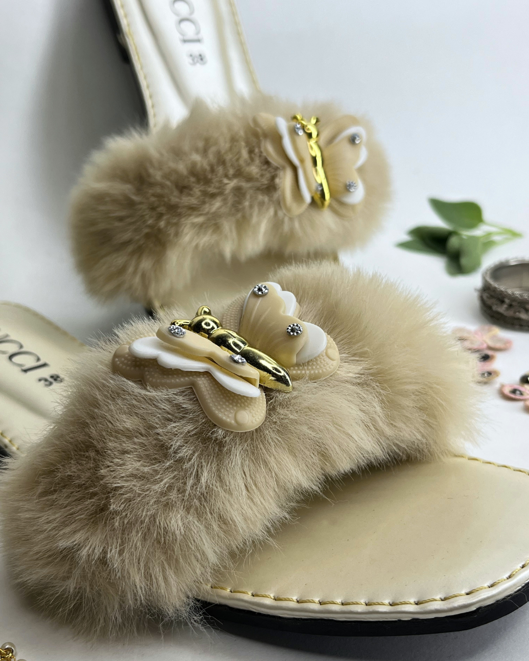 Women comfort slides with fluffy fur strap and butterfly embellishment on a light background