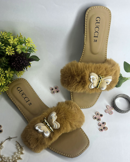 Beige women slides with fluffy fur strap and butterfly embellishment on a light background