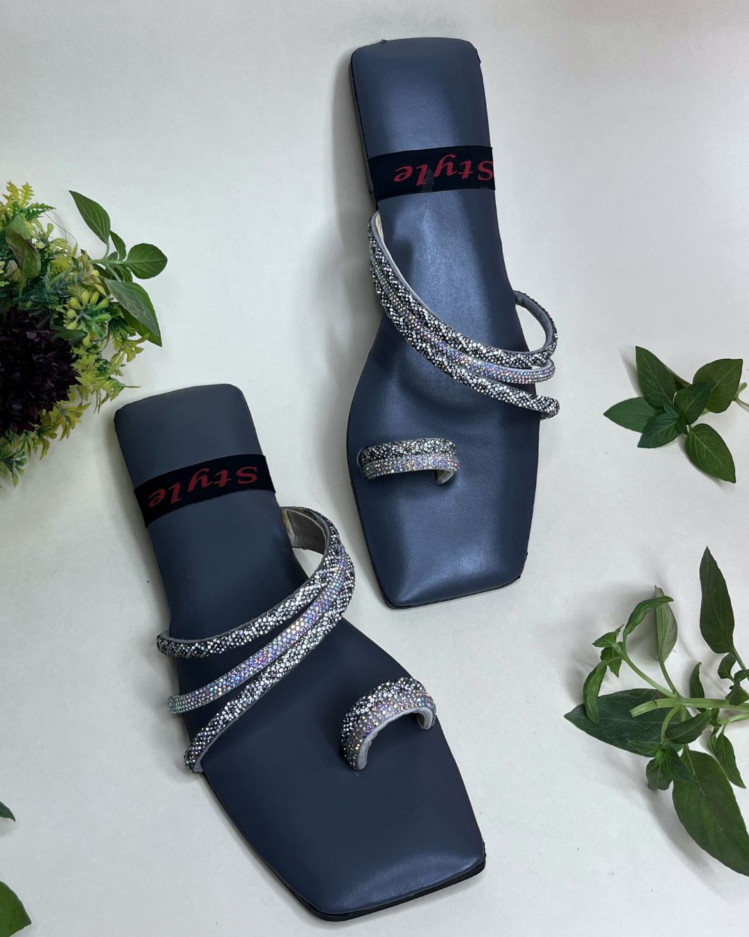 Grey women flats with crystal spiral detailing on a light background