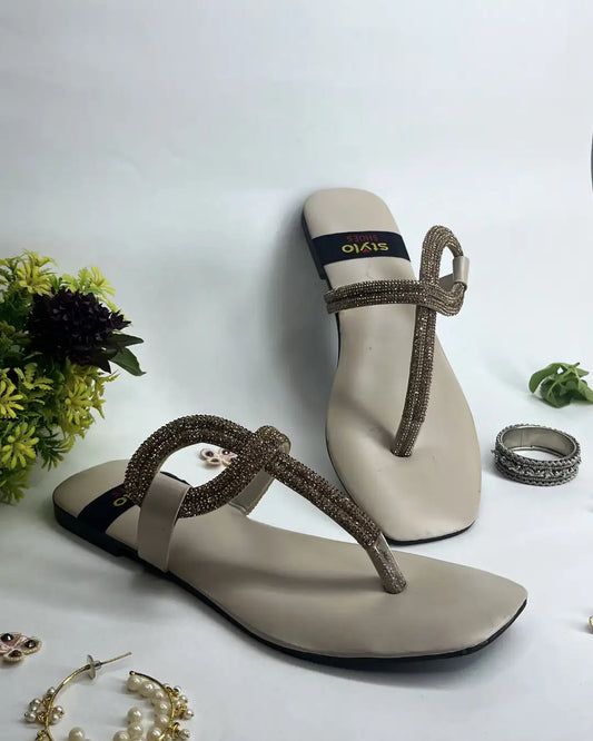 Women elegant flats with crystal loop strap design on a light background