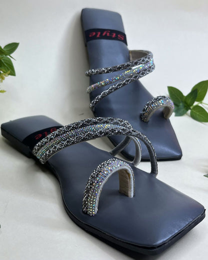 Grey women flats with crystal spiral detailing on a light background