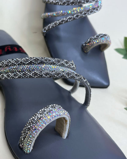 Grey women flats with crystal spiral detailing on a light background