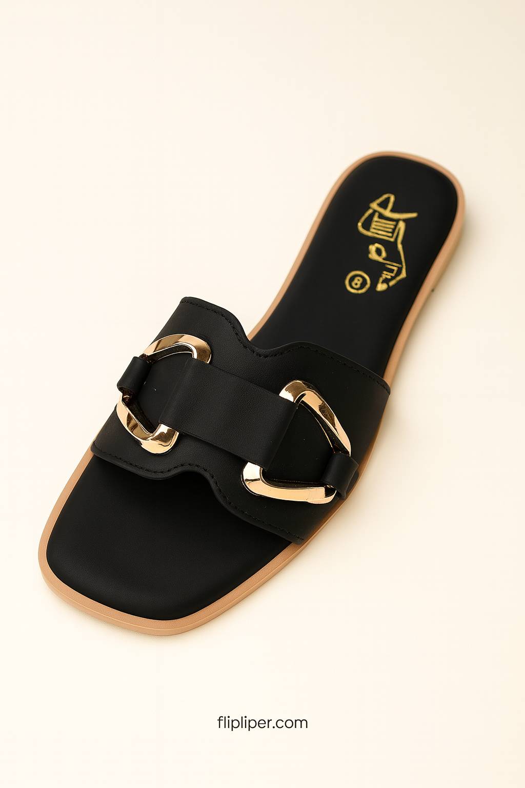 Pair of black sandals with gold buckles displayed on a beige background
