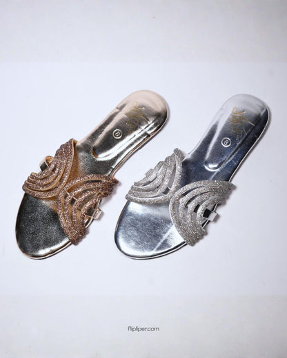 Person wearing gold embellished sandals while standing on a tiled floor
