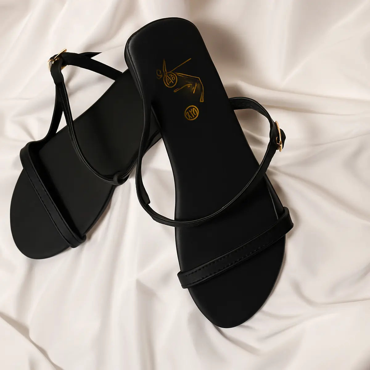 Flip Liper black flat sandals worn with blue jeans while standing on a stone pathway in an outdoor natural setting
