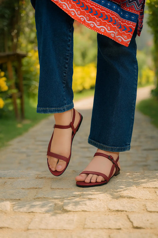 Flip Liper maroon flat sandals worn with blue jeans while walking on a stone pathway in a natural outdoor setting
