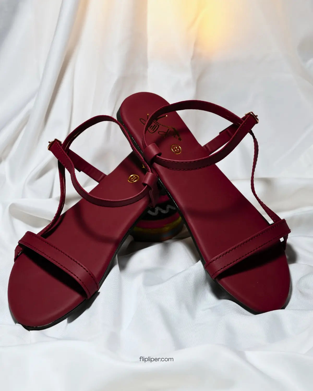 Flip Liper maroon flat sandals worn with blue jeans while walking on a stone pathway in a natural outdoor setting
