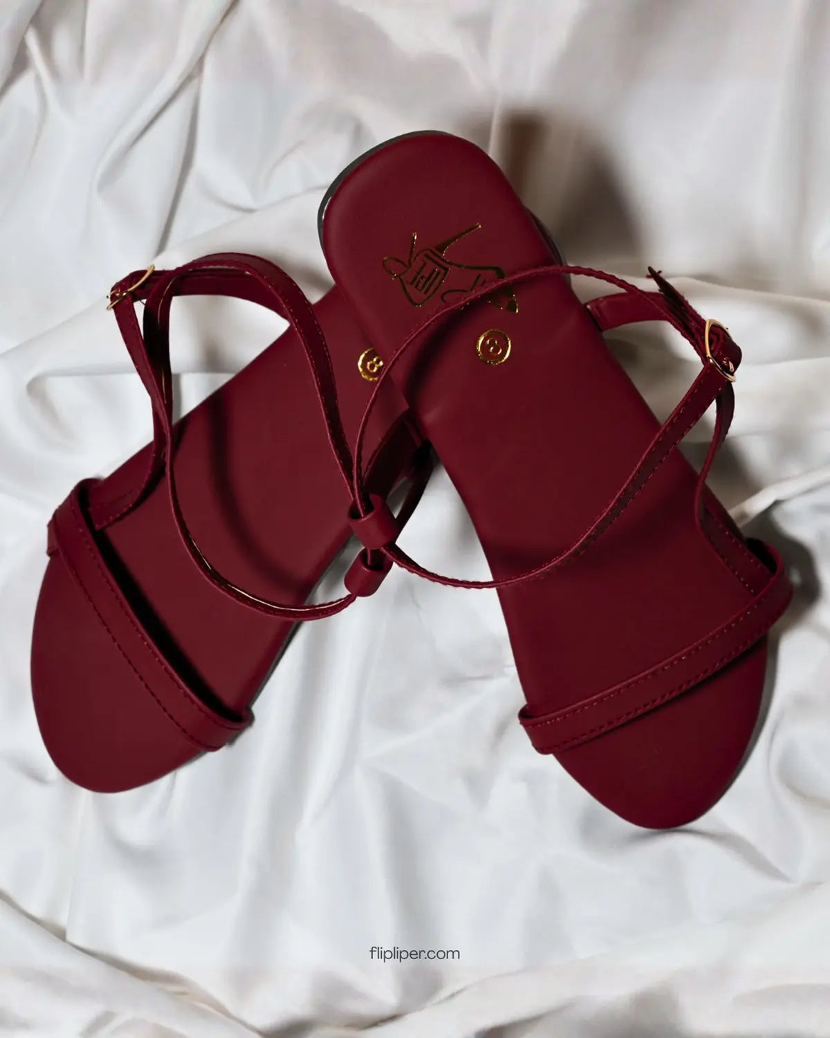 Flip Liper maroon flat sandals worn with blue jeans while walking on a stone pathway in a natural outdoor setting
