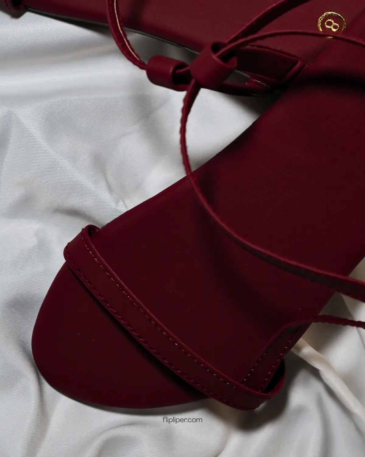 Flip Liper maroon flat sandals worn with blue jeans while walking on a stone pathway in a natural outdoor setting
