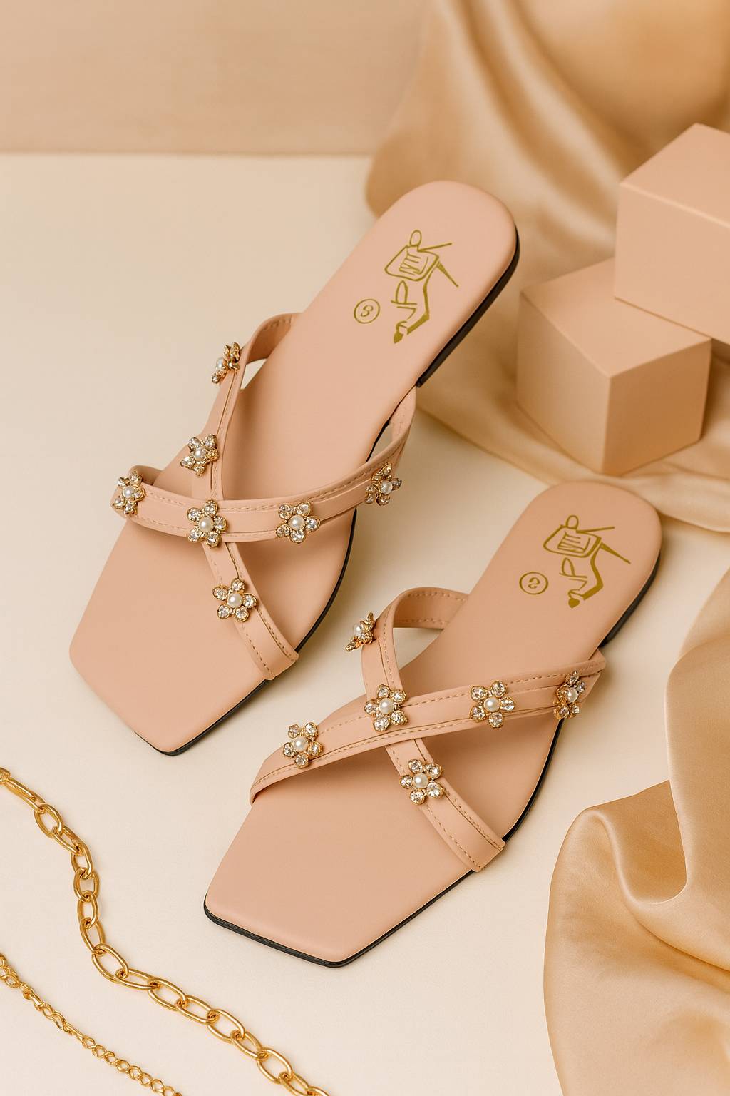 Pink sandals with decorative floral straps placed on a beige fabric background
