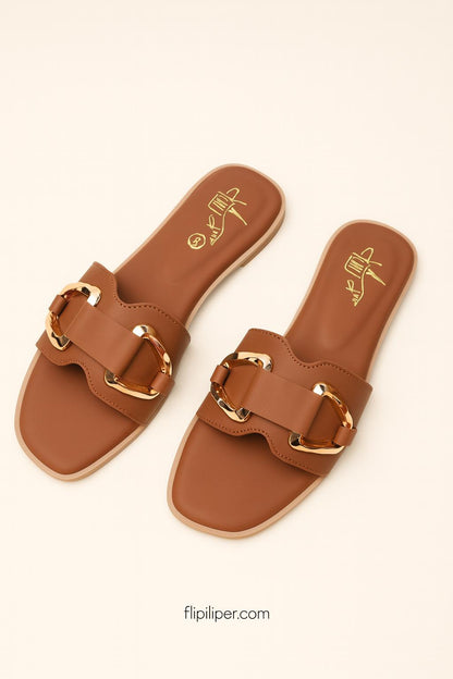 Pair of brown sandals with gold buckles displayed on a beige background
