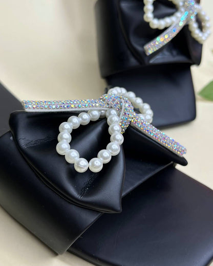 Black women luxe flats with pearl bow detailing on a light background