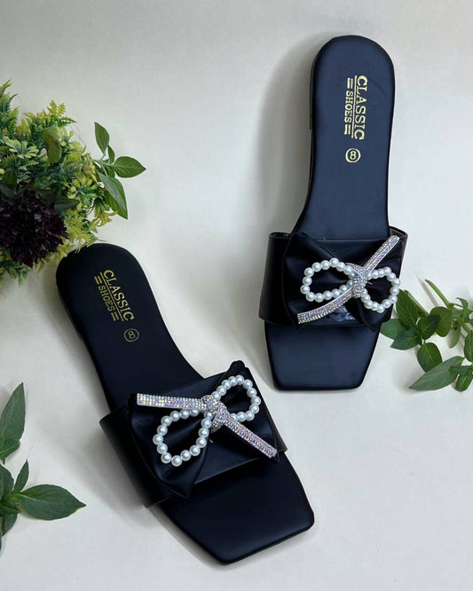 Black women luxe flats with pearl bow detailing on a light background