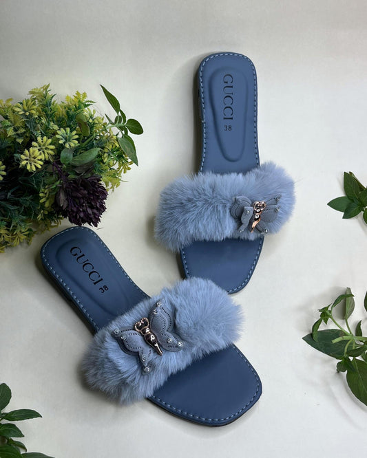 Blue Gucci style fluffy fur strap women slides with metallic detail on a light background